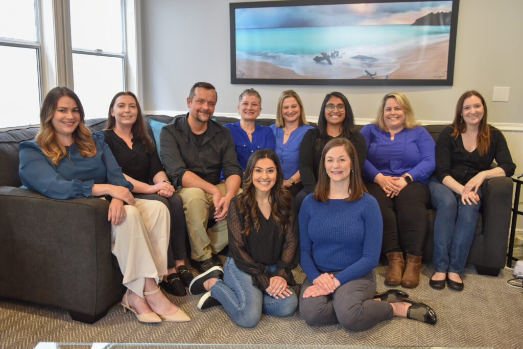 A diverse group of eight people posing in a living room.