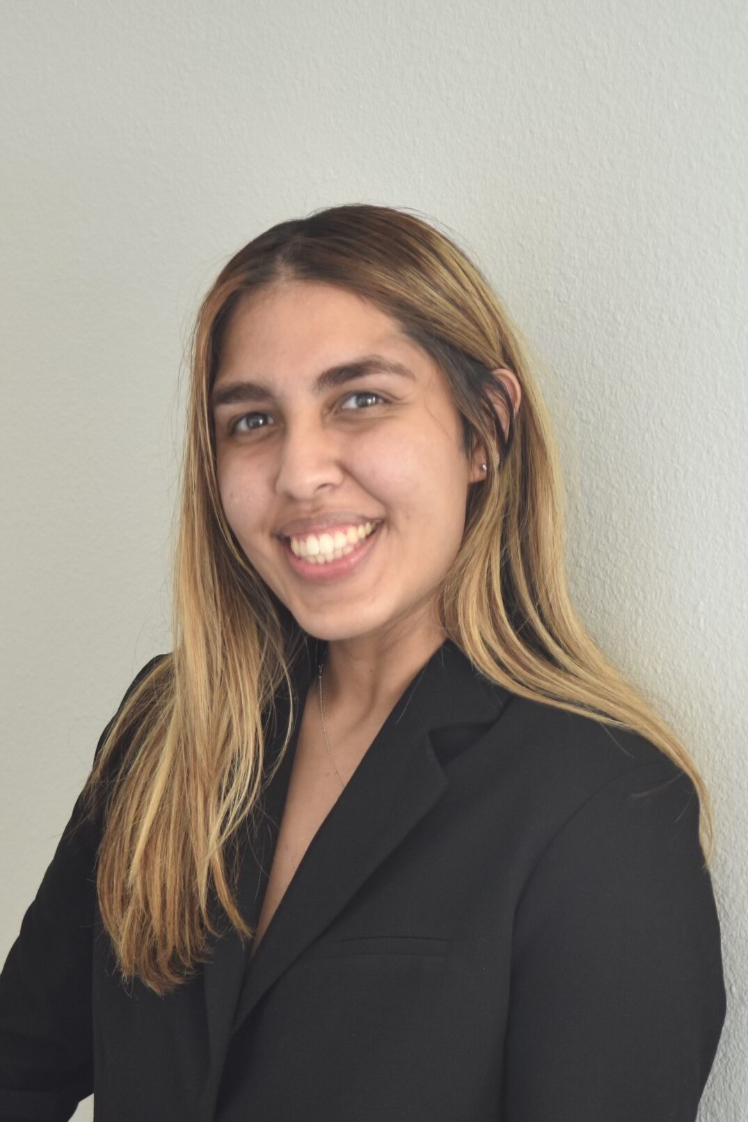 A confident woman in a black suit smiling.